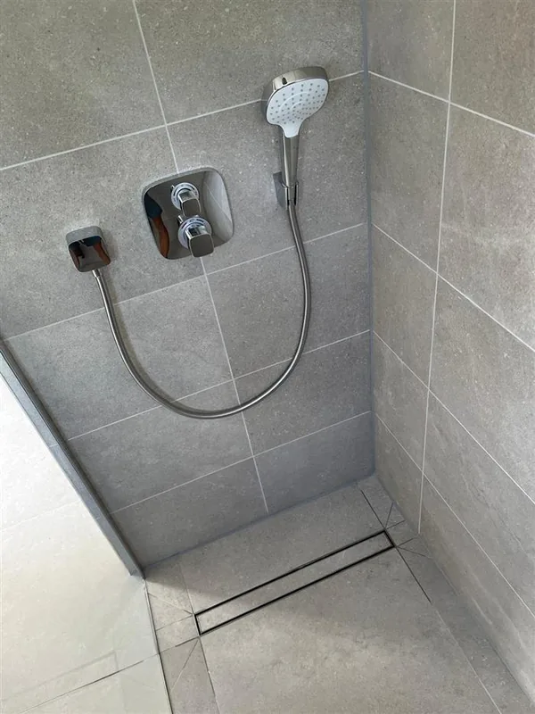 Handheld shower on grey stone tiling