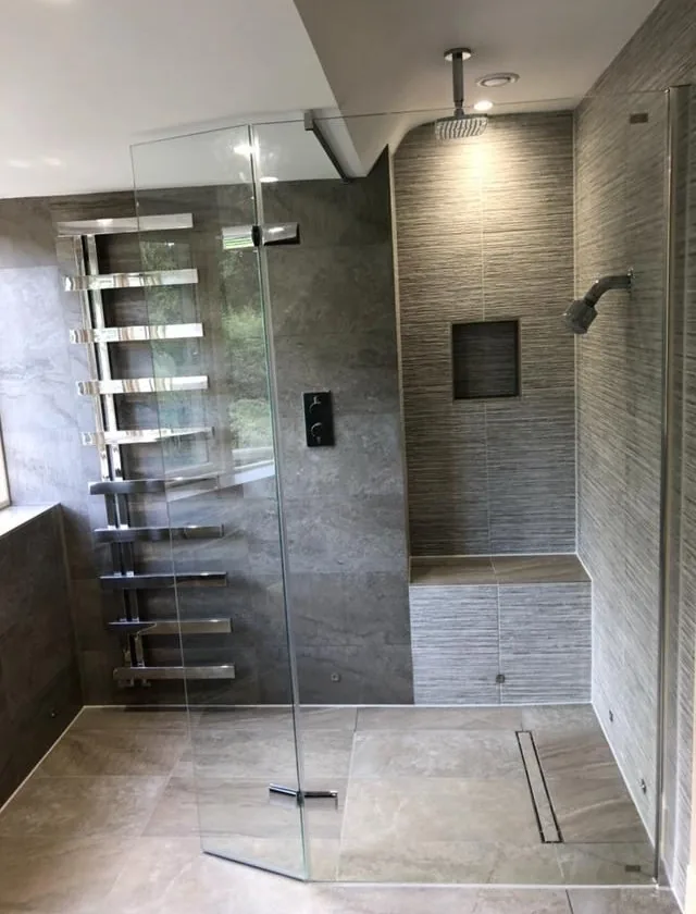 Frameless walk-in wet room with rainfall shower head and tiled bench